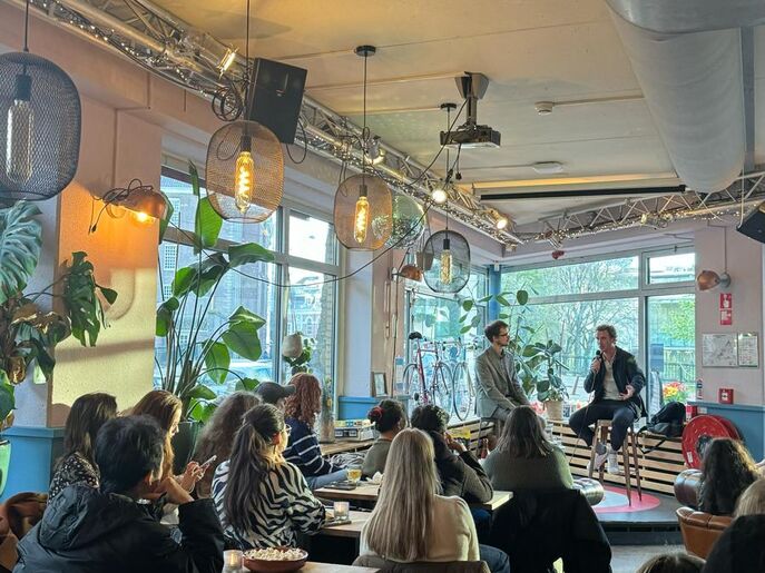 Café De Krater with students and on stage the guest speakers.